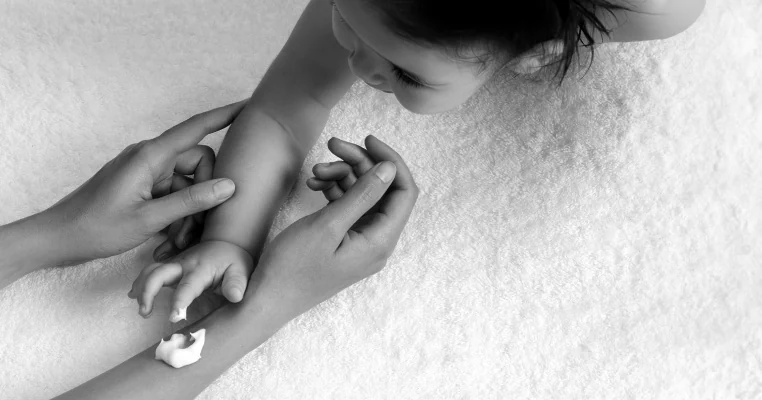 Ребёнок наносит крем на женские руки